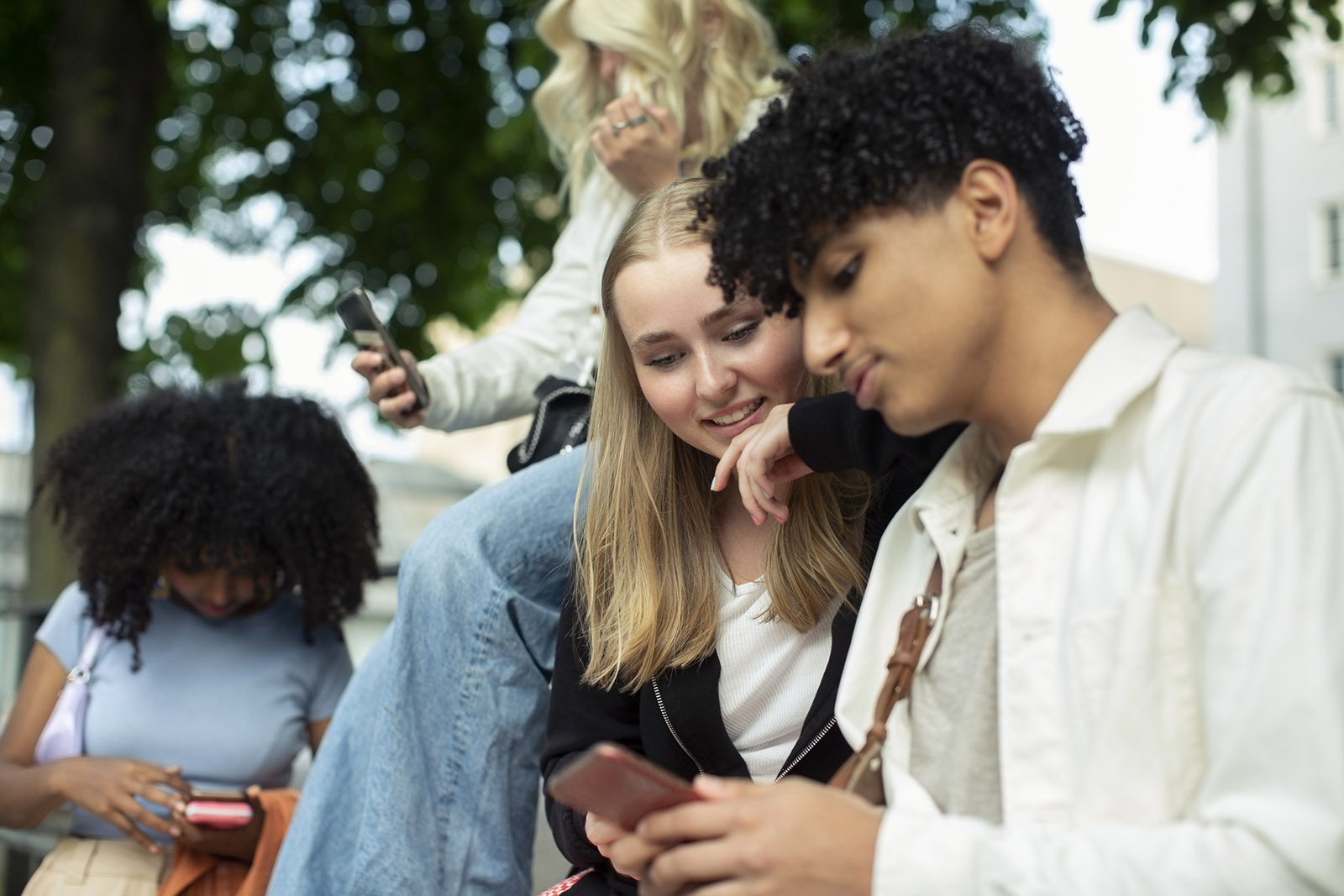 Fyra ungdomar utomhus som håller i mobiler