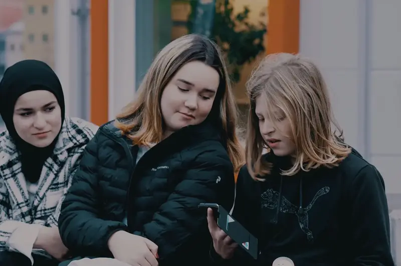 Tre ungdomar med en telefon.
